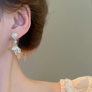 Détail de boucle d'oreille perle élégante avec pendentif fleur 3D blanche sur modèle