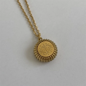 Close-up of golden Sagittarius zodiac pendant with bow-and-arrow engraving and ribbed edges