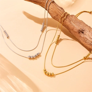 Double-layered stainless steel ball bead necklaces in gold and silver on wood background