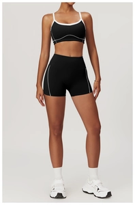 Detail of black sports set with white contrast piping on crop top and high-waisted shorts