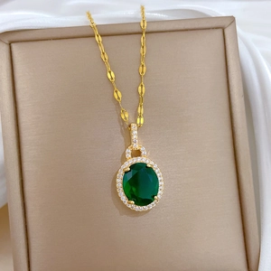 Détail d'un pendentif goutte en zircon vert avec chaîne dorée dans un coffret beige