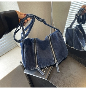 Détail du sac bandoulière en denim bleu foncé avec double fermeture éclair argentée