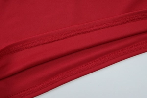Close-up of red knit fabric showing fine stitching and detailed texture on backless top