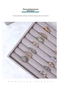 Macro detail of various gold and silver rings displayed in a beige velvet jewelry tray