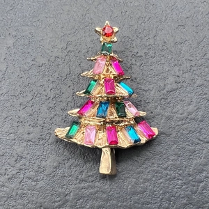Detailed shot of Christmas tree brooch with multicolored crystals on a golden base