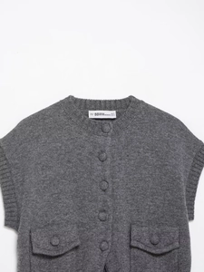 Détail macro du gilet en tricot gris foncé avec texture en laine et poches boutonnées