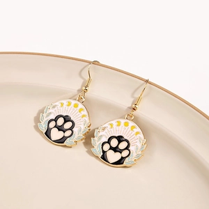 Macro shot of cute cartoon cat paw and moon dangle earrings on a ceramic dish