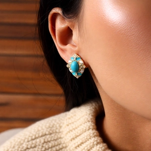 Gros plan de boucles d'oreilles vintage en or avec turquoise et émail blanc sur mannequin