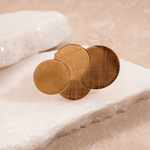 Macro detail of golden brushed metal geometric discs on a textured white stone base