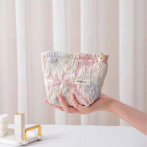 Elegant floral embossed makeup bag in pastel pink and purple with golden petal zipper