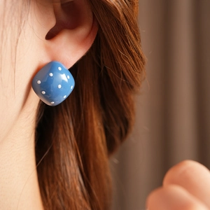 Nahaufnahme eines blauen quadratischen Polka-Dot-Ohrrings im Vintage-Stil am Model