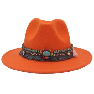 Detailed shot of ethnic embroidery band with turquoise and colorful tassels on orange hat