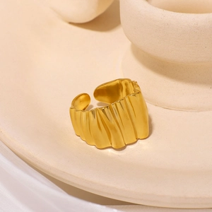 Golden wavy textured open ring in 18K gold plated stainless steel on a ceramic tray