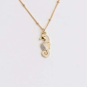 Detail of seahorse pendant necklace with white enamel inlay and gold bead chain accent