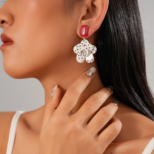 Detailed view of polka dot flower earring with red jewel accent on model's ear
