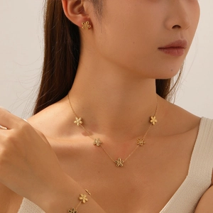 Detailed close-up of matte gold flower-shaped necklace, earrings and bracelet set