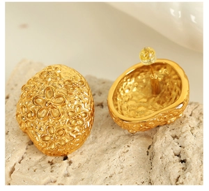 Detailed macro view of 18k gold plated square woven earrings with floral relief designs