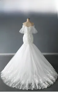 Detail of off-shoulder wedding dress with puff sleeves, lace patterns, and beaded bodice
