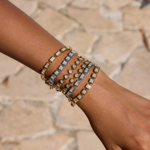 Close-up of stacked gold and silver tennis bracelets with zircon stones on model's wrist