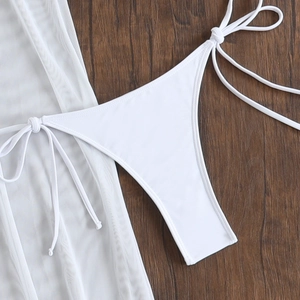Detailed flat lay of white bikini bottoms and matching mesh cover-up with drawstring ties