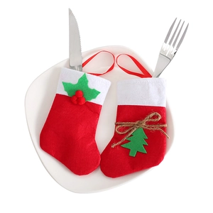 Detail of red felt Christmas cutlery holders with holly and tree motifs on white plate
