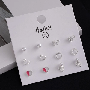 Detailed close-up of 6 pairs of silver stud earrings including pearls and hearts