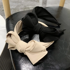 Detail of layered black and beige bow headbands on a textured black leather chair