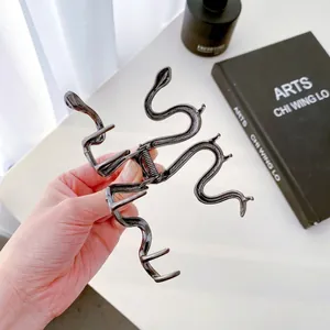 Minimalist glossy black metal snake-shaped hair claw clip with detailed skin texture