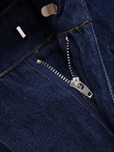 Κοντινό πλάνο ραφής denim με ανθεκτικό μεταλλικό φερμουάρ και λεπτομέρεια γάντζου