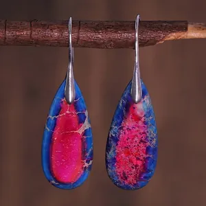Detailed view of teardrop stone earrings hanging on a natural wooden branch