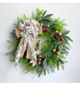Close-up of Christmas wreath with pine cones, golden bells and burlap bow decoration
