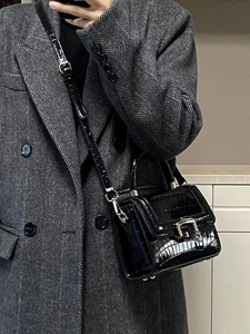 Detail of black crocodile pattern crossbody bag with silver hardware and adjustable strap