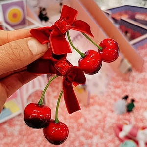 Gros plan sur une barrette en velours rouge avec pendentifs cerise et cristaux taillés