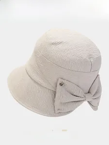 Detailed view of the textured pleats and decorative bow on an elegant beige sun hat