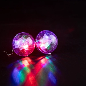Macro shot of glowing purple disco ball earrings with colorful LED light reflections