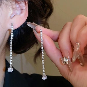 Close-up of silver tassel earrings with sparkling rhinestones worn by a model