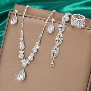 Close-up of sparkling waterdrop zircon necklace and earrings on green satin fabric