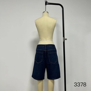 Detail view of heavy wash dark blue denim shorts with orange contrast stitching details