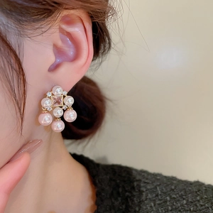 Detail of gold plated earrings with pink square zircon and pearl tassels on a model
