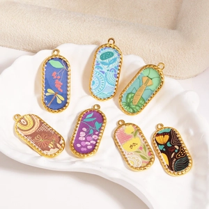 Close-up of retro koi and floral embroidery charms in gold metal frames on a shell plate