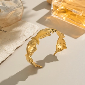Close-up of golden open bangle featuring an intricate continuous fish pattern relief