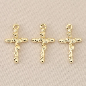 Detailed view of three vintage 18K gold-plated baroque cross pendants with vine patterns