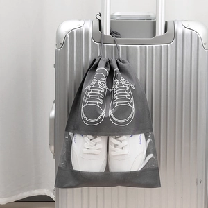 Travel non-woven shoe storage bag with clear window shown on suitcase handle