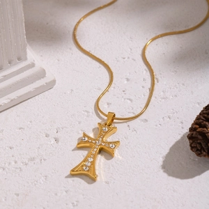 Gros plan du pendentif croix dorée incrusté de zircon sur chaîne serpent raffinée