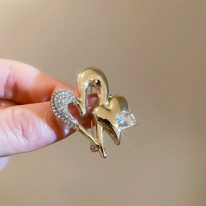 Detailed view of intertwined golden heart brooch with sparkling zircons and square stone