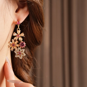 Close-up of vintage flower earrings with pink gems and diamonds on female model