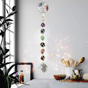 Rainbow light reflection from Tree of Life crystal suncatcher and chakra stones on window