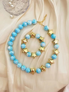 Vista dettagliata del set di collana e bracciale con perle blu e stelle dorate.