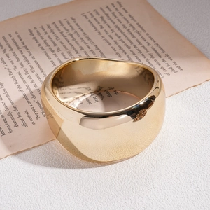Polished gold wide band ring on vintage book pages with a luxury mirror finish look