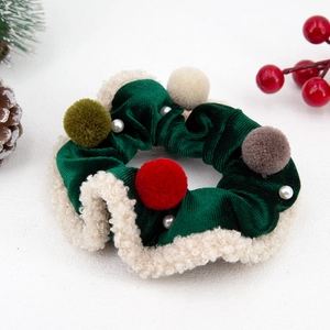 Close-up of Christmas velvet scrunchie with plush trim and festive pom-pom decorations